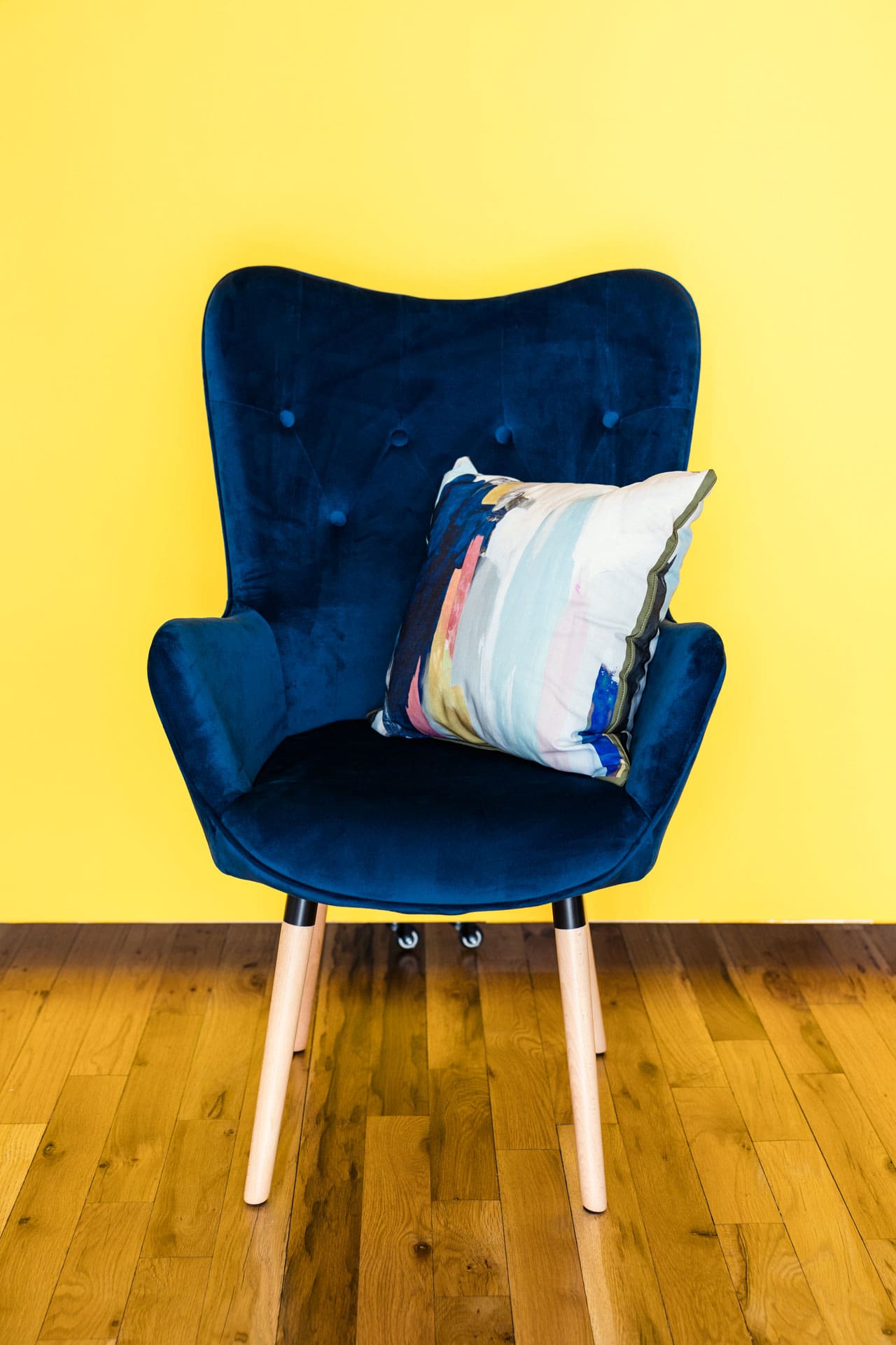 Blue velvet accent chair and colorful pillow with yellow backdrop available at Chicago photography studio P&M Studio