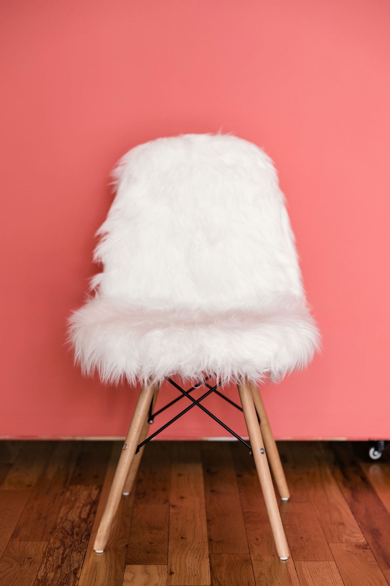Fluffy white accent chair against coral backdrop available for photo shoots at P&M Studio Chicago