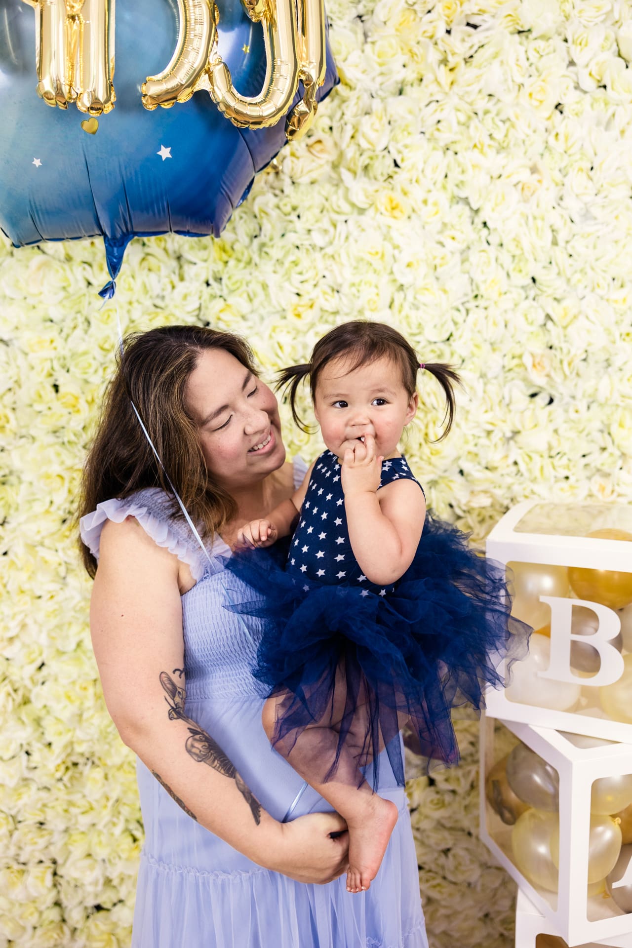 Mom holds toddler on her baby bump while holding blue balloon during familly photoshoot at Chicago photography studio P&M Studio