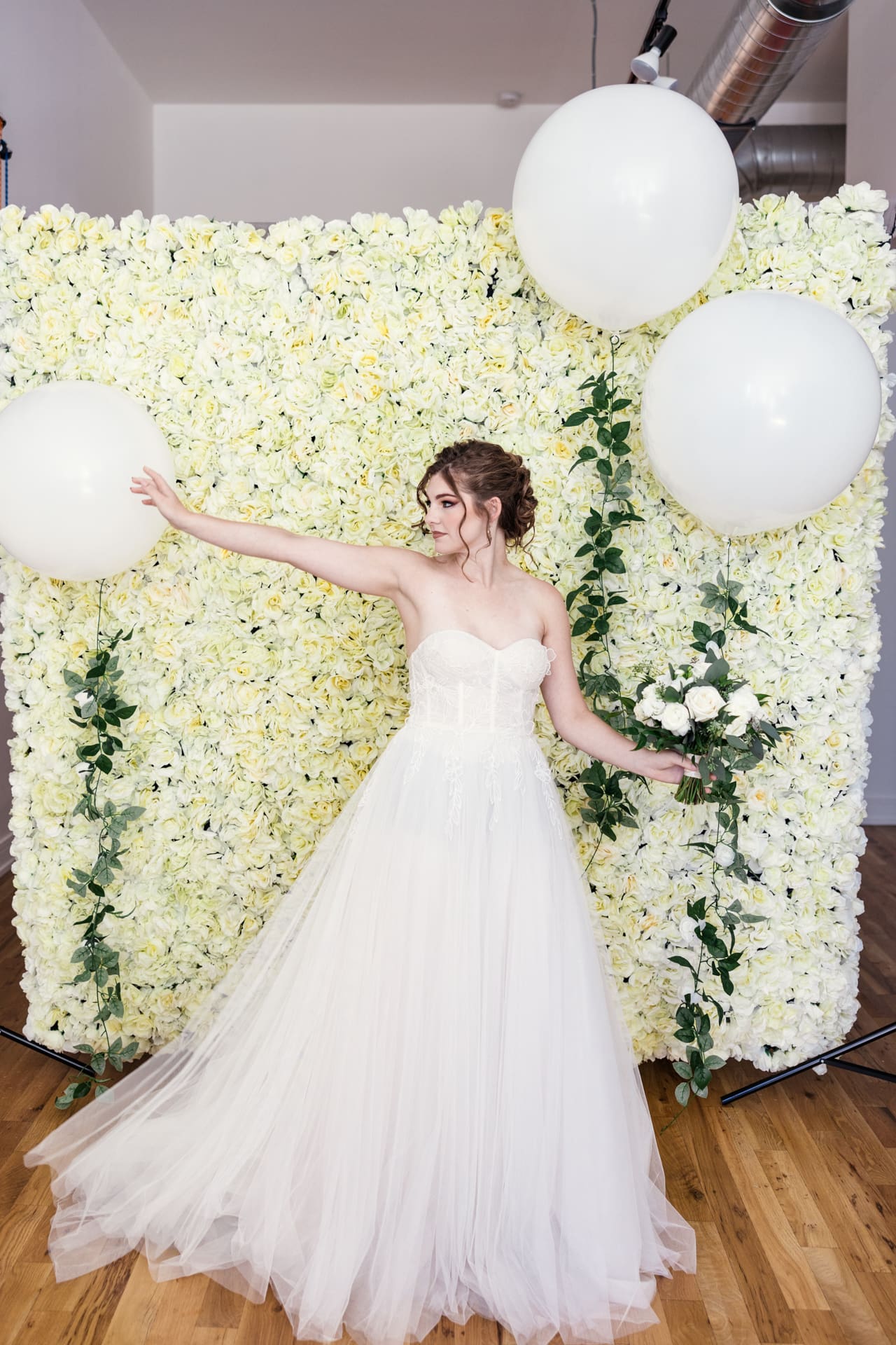 Fun photo of bride with giant white balloons and white floral backdrop at Chicago photography studio P&M Studio