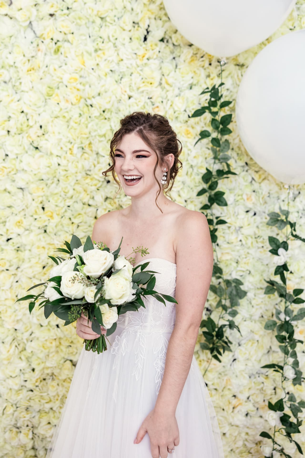 Candid photo of bride laughing in front of white floral backdrop at Chicago photography studio P&M Studio