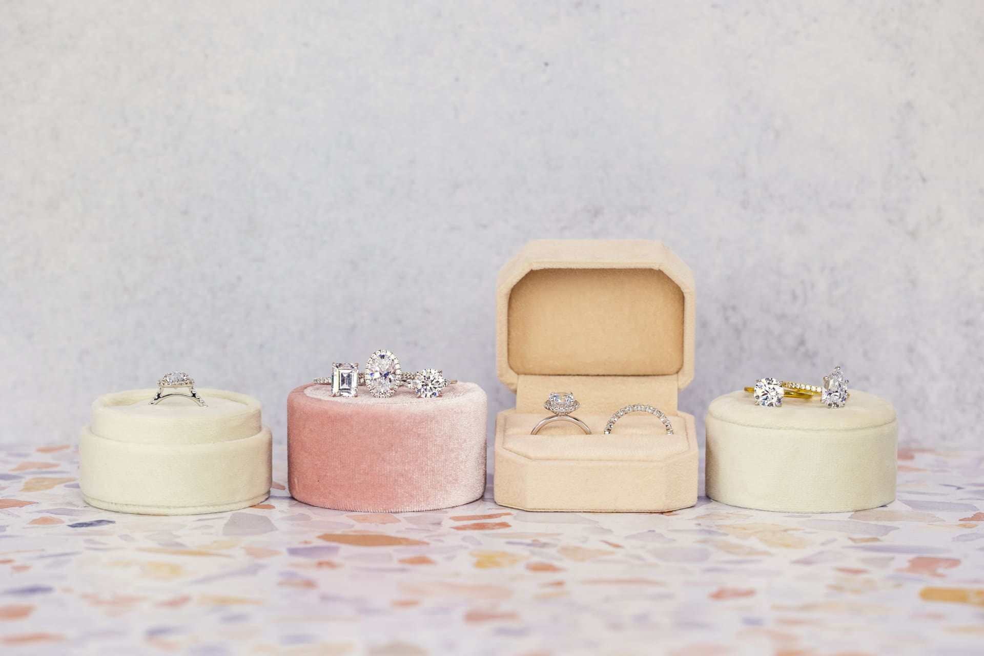 Jewelry product photography of multiple diamond rings inside pink, peach, and white velvet ring boxes on tile counter at Chicago photography studio P&M Studio