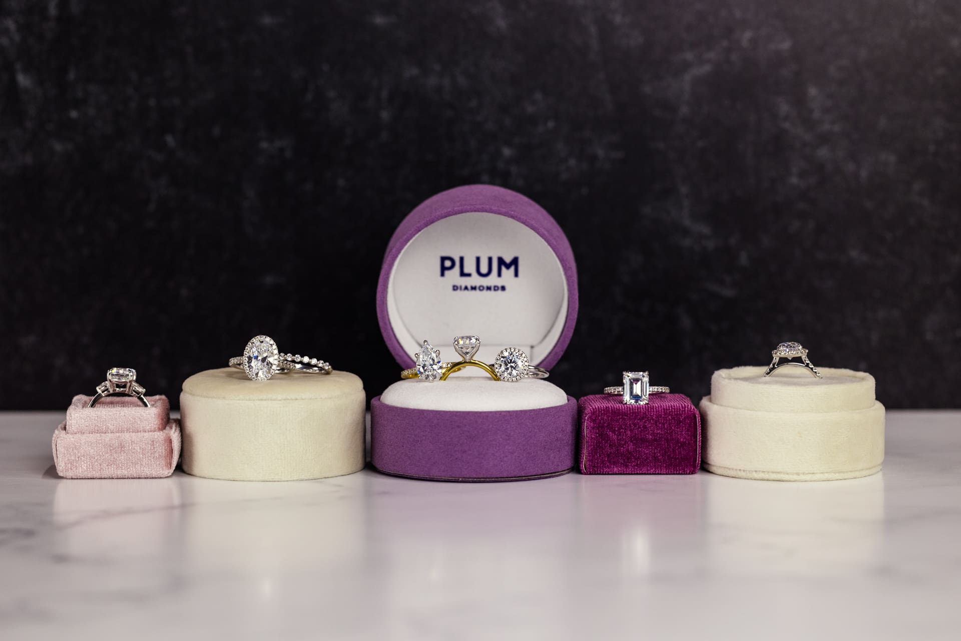 Jewelry product photography for Plum Diamonds featuring multiple diamond engagement rings in velvet boxes with black background at Chicago photography studio P&M Studio
