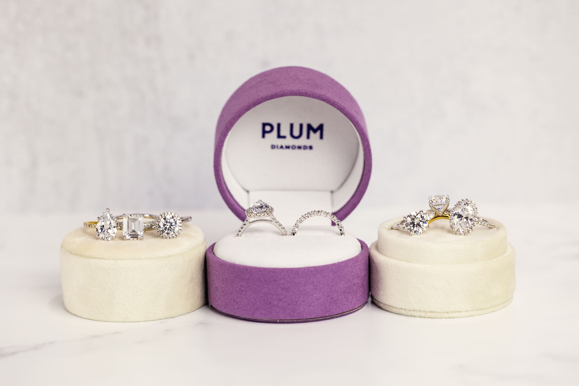 Variety of diamond engagement rings on display in velvet boxes with purple Plum Diamonds logo at Chicago photography studio P&M Studio