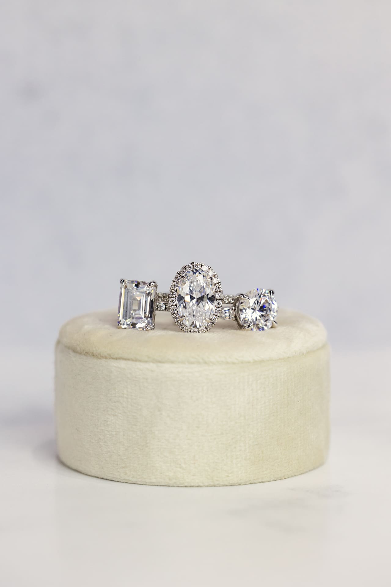 Detail photo of three unique diamond rings sitting on white velvet ring box with dove gray background at Chicago photography studio P&M Studio