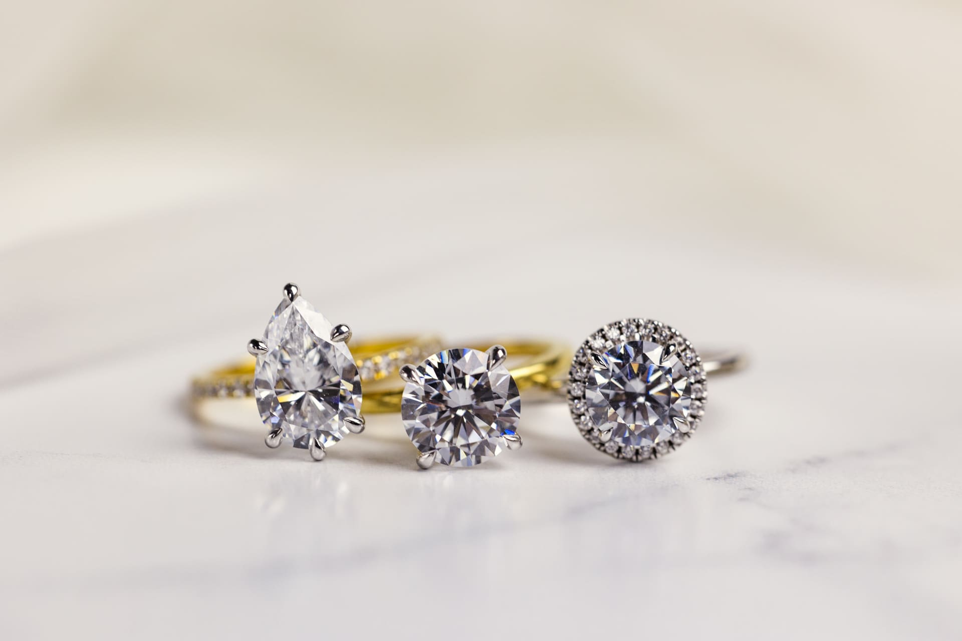 Detail photo of three diamond engagement rings on white marble counter at Chicago photography studio P&M Studio