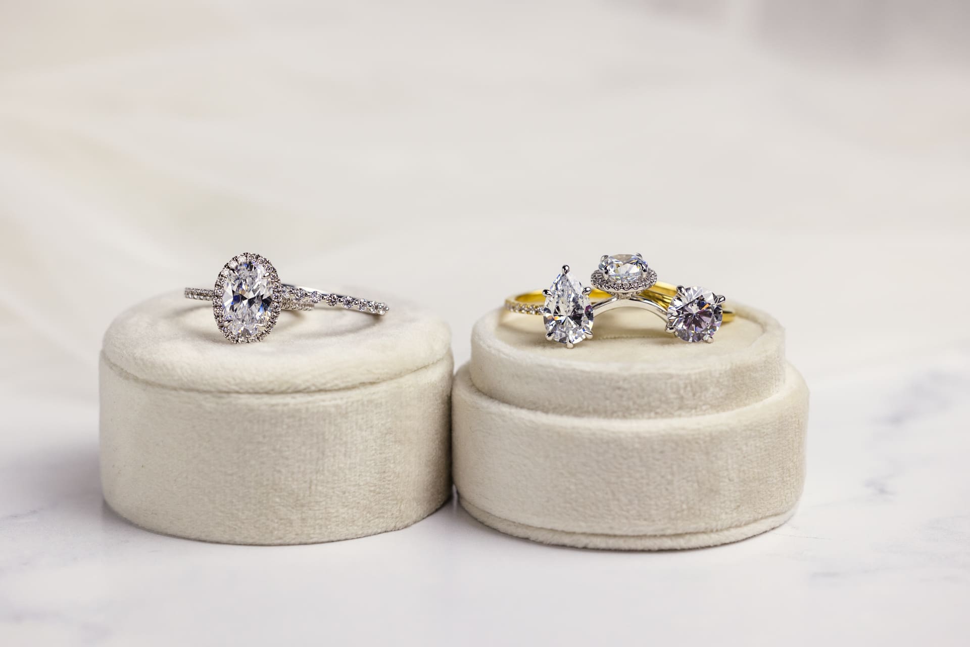 Diamond engagement rings and wedding bands in a variety of cuts sit on white velvet ring box on marble counter at Chicago photography studio P&M Studio