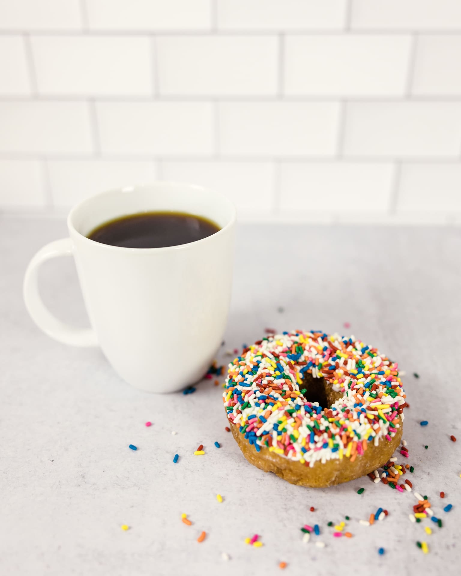 Cup of Dark Matter coffee and Birthday Cake donut by Do-Rite Donuts sit on kitchen counter at Chicago photography studio P&M Studio