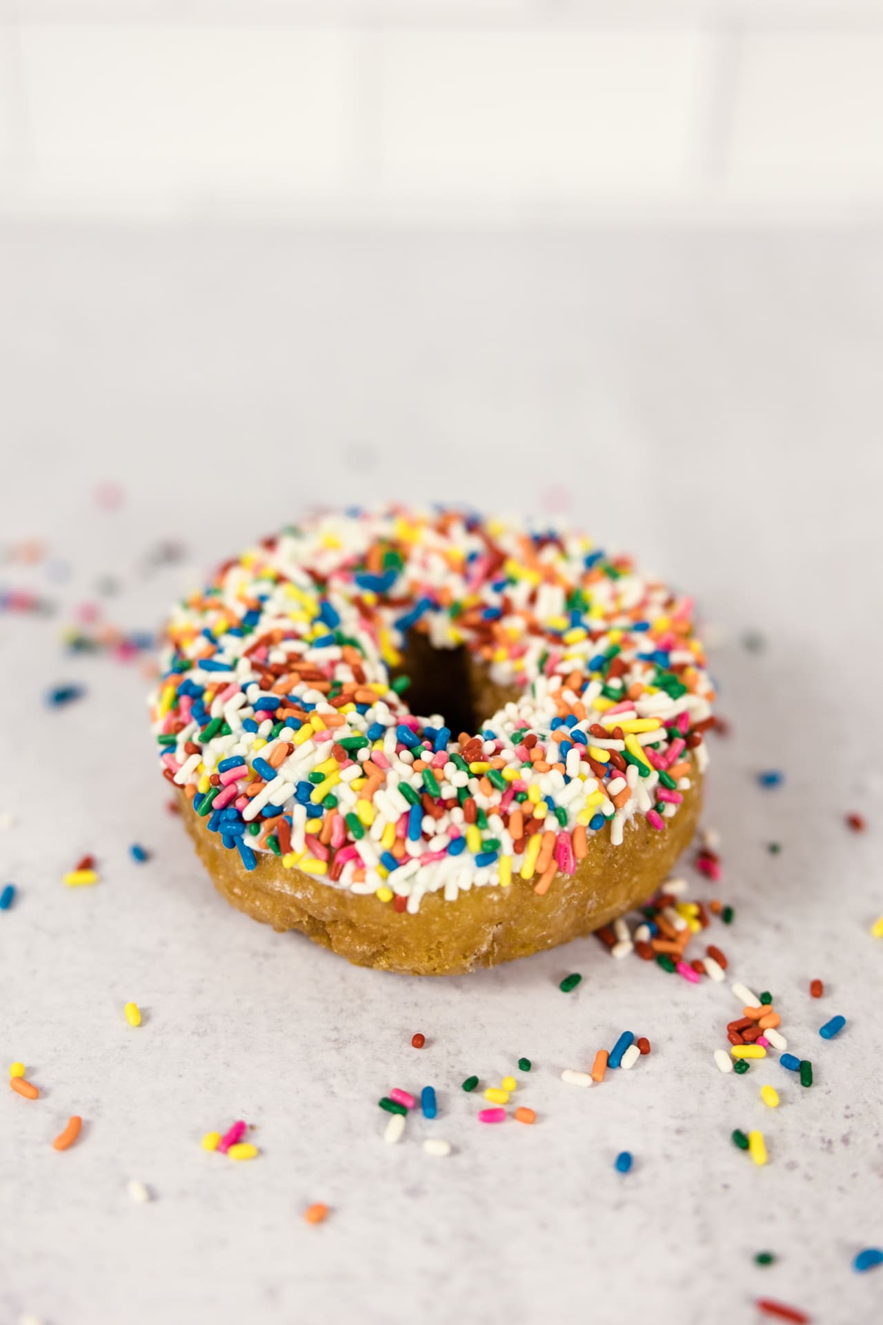 Detail photo of colorful sprinkle donut sitting on kitchen counter with sprinkles on counter at Chicago photography studio P&M Studio