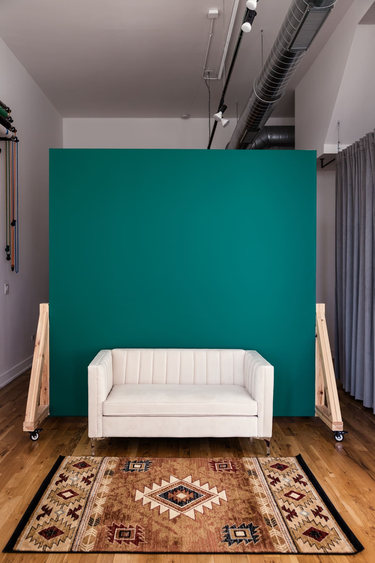One side of mobile wall with teal green color and cream-colored velvet sofa inside natural light photography studio P&M Studio Chicago