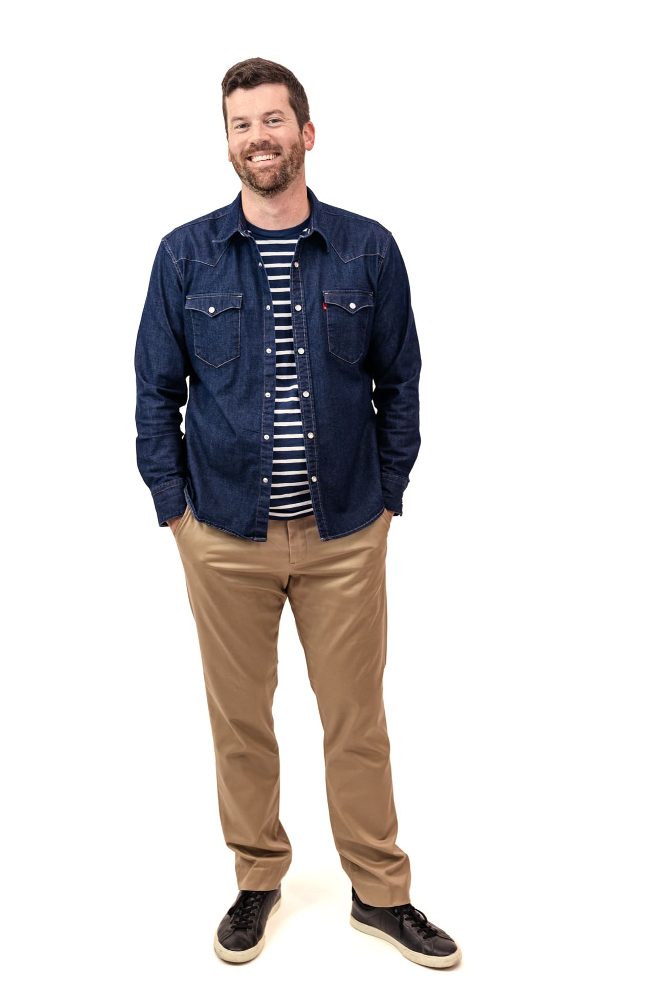 Studio portrait of man wearing denim shirt and khaki pants with sneakers on white backdrop at Chicago photography studio P&M Studio