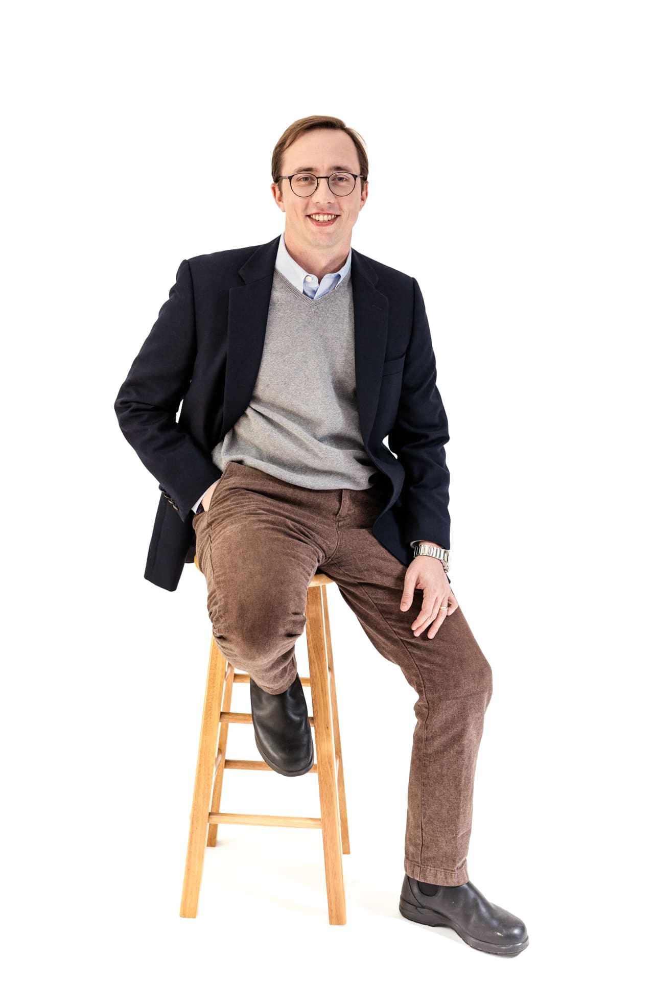 Studio portrait of man wearing business casual jacket and brown pants sitting on stool at Chicago photography studio P&M Studio